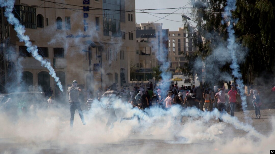 Para demonstran Palestina berlarian dari gas air mata yang ditembakkan oleh tentara Israel dalam bentrokan dekat Ramallah, Tepi Barat (17/10). (AP/Majdi Mohammed)