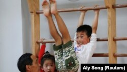 Seorang anak laki-laki berlatih sebagai asisten pelatihnya selama pelajaran senam di Shanghai Yangpu Youth Amateur Athletic School di Shanghai, Cina, 4 Mei 2016. (Foto: Reuters/Aly Song)