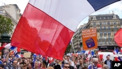 Protesters hold signs that read in French "freedom" and "no to the vaccine passport" as they attend a demonstration in Paris, July 31, 2021.