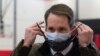 Congressman Jim Himes adjusts his two masks during a tour of a vaccination clinic, Feb. 10, 2021, at a high school in Bridgeport, Conn.