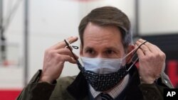 Congressman Jim Himes adjusts his two masks during a tour of a vaccination clinic, Feb. 10, 2021, at a high school in Bridgeport, Conn.