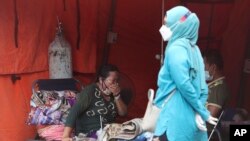 A woman sits inside an emergency tent accommodating a surge of COVID-19 patients at a hospital in Bekasi, West Java, Indonesia.