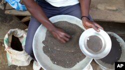 FILE - A Congolese miner sifts through ground rocks to separate cassiterite, the main ore that’s processed into tin, in the town of Nyabibwe, eastern Congo, a once bustling outpost fueled by artisanal cassiterite mining, Aug. 16, 2012.