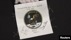  $62 mil 500 por este emblema firmado por los astronautas Michael Collins, Edwin Aldrin y Neil Armstrong en una subasta previa.