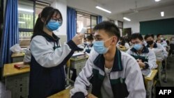Siswa SMA memeriksa suhu tubuh rekan-rekannya pada pembukaan kembali sekolah di kota Wuhan, Hubei, China (foto: ilustrasi). 