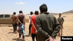 FILE - Men who the Syrian Democratic Forces claimed were Islamic State fighters walk as they are taken prisoner after SDF advanced in the southern rural area of Manbij, in Aleppo Governorate, Syria, May 31, 2016. 