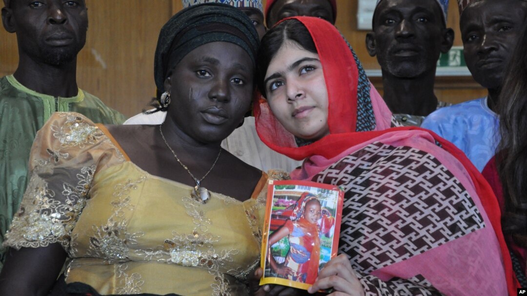 Pakistani activist Malala Yousafzai, who survived being shot by the Taliban because she advocated education for girls, holds a picture of kidnapped schoolgirl Sarah Samuel with her mother Rebecca Samuel, while visiting Abuja, Nigeria, July 13, 2014. 