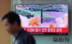 FILE - A man walks past a TV screen showing a local news program about North Korea's reported firing of an ICBM, at Seoul Train Station in Seoul, South Korea, July 5, 2017.