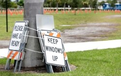 Signs lashed to a palm tree are shown at a closed COVID-19 testing site at the FITTEAM Ballpark of The Palm Beaches Saturday, Aug. 1, 2020, in West Palm Beach, Fla. Hurricane Isaias is headed toward the Florida coast, where officials have closed…