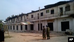 In this photo taken with a mobile phone, soldiers stand outside a burnt out shopping mall in Maiduguri, Nigeria, Monday, Oct. 8, 2012.