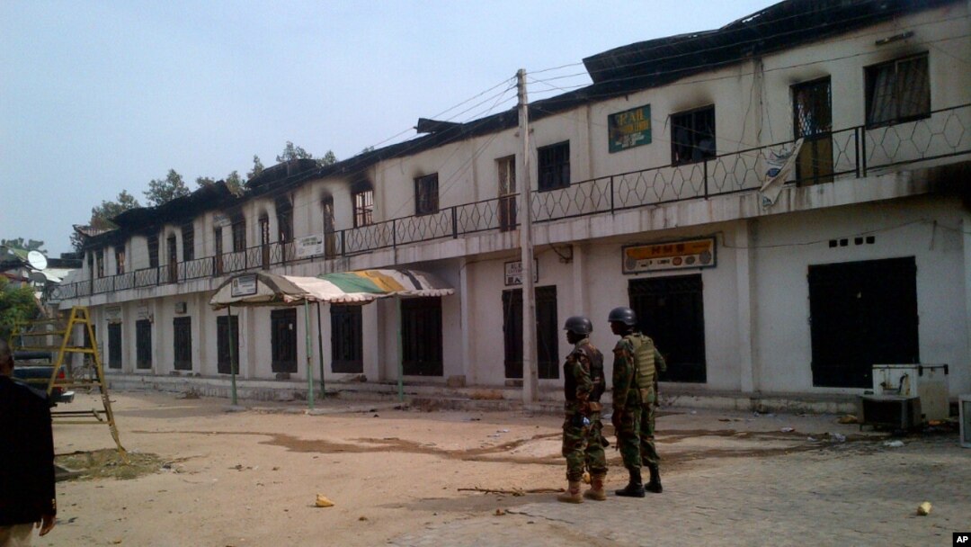 Tentara Nigeria berjaga di luar sebuah pertokoan yang terbakar di Maiduguri, Nigeria (8/10).