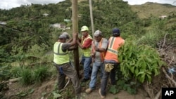 Public Works Sub-Director Ramon Mendez, wearing hard hat, directs locals who are municipal workers, Eliezer Nazario, holding rope, Tomas Martinez, right, and Angel Diaz, left, as they install a power pole in an effort to return electricity to Felipe Rodri
