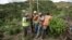 Public Works Sub-Director Ramon Mendez, wearing hard hat, directs locals who are municipal workers, Eliezer Nazario, holding rope, Tomas Martinez, right, and Angel Diaz, left, as they install a power pole in an effort to return electricity to Felipe Rodri