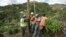 Public Works Sub-Director Ramon Mendez, wearing hard hat, directs locals who are municipal workers, Eliezer Nazario, holding rope, Tomas Martinez, right, and Angel Diaz, left, as they install a power pole in an effort to return electricity to Felipe Rodriguez's home, four months after Hurricane Maria in Coamo, Puerto Rico, Jan. 31, 2018.
