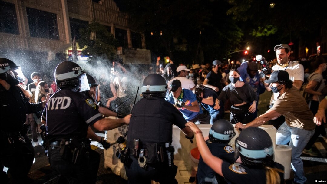 A police officer sprays protesters during a march against the death in Minneapolis police custody of George Floyd, in the Brooklyn borough of New York City, May 30, 2020. 