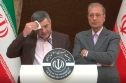 FILE - The head of Iran's counter-coronavirus task force, Iraj Harirchi, left, wipes his face during a press briefing with government spokesman Ali Rabiei, in Tehran, Iran, in this Feb. 24, 2020, image made from video.