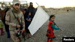 FILE - A girl who had just fled Kokjali near Mosul carries a white flag as she arrives with her family at a peshmerga checkpoint east of Mosul, Iraq, Nov. 3, 2016. 