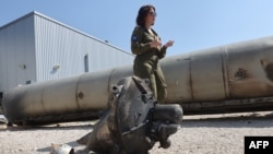 Pripadnica izraelske vojske stoji pored ostataka oborene iranske balističke rakete koja je pala u Izrael pršlog vikenda, tokom obilaska organizovanog za medije u vojnoj bazi Džulis, na jugu Izraela, nedaleko od grada Kirjat Malači, 16. aprila 2024.