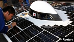 FILE - A members of Japan's team at a previous World Solar Challenge is seen cleaning a solar panel on his vehicle.