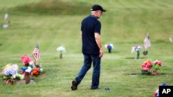 Eddie Davis walks past tributes on his way to his son Jeremy's gravestone, who died from the abuse of opioids, July 17, 2019, in Coalton, Ohio.