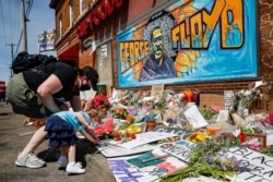 Jessica Knutson, and her daughter Abigail, 3, place flowers at a memorial to George Floyd, May 31, 2020, in Minneapolis.