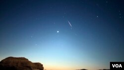 Sebuah meteor melintas di langit saat hujan meteor Perseid di Valley of Whales, di Fayoum, Egypt, 12 Agustus 2017. (H. Elrasam/VOA)