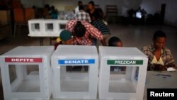 FILE - Haitian workers from the Provisional Electoral Council organize ballots.