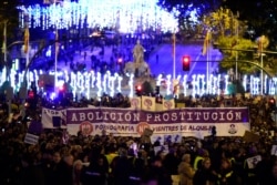 FILE - Women hold a giant banner reading 'Abolition of prostitution' during a demonstration to mark the International Day for the Elimination of Violence against Women in Madrid on Nov. 25, 2019.