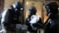 FILE - A U.N. chemical weapons expert, wearing a gas mask, holds a plastic bag containing samples from one of the sites of an alleged chemical weapons attack in Ain Tarma neighborhood of Damascus, Syria, Aug. 29, 2013.