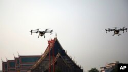 Beberapa drone terlihat menyemprotkan air, melintasi atap Kuil Suthat di Bangkok, Thailand, 31 Januari 2019.