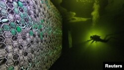 A diver uses a torch to explore artworks under the ice of the White Sea off the coast of the Republic of Karelia, Russia. (Courtesy of Viktor Lyagushkin)