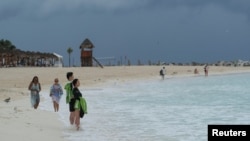 Tourists stand on a beach as Tropical Storm Helene approaches the Yucatan Peninsula, in Cancun, Mexico Sept. 24, 2024. 