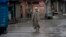 A Kashmiri man walks as Indian paramilitary soldiers stand guard during security lockdown in Srinagar, Indian controlled Kashmir, Wednesday, Aug. 14, 2019.
