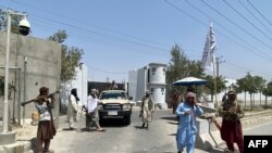 Taliban fighters stand guard at an entrance gate outside the Interior Ministry in Kabul, August 17, 2021.