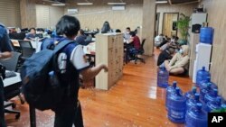 Dalam foto selebaran yang disediakan oleh Polisi Nasional Filipina, tampak seorang polisi berjalan di dalam salah satu kantor kejahatan siber yang mereka razia di kota Las Pinas, Filipina hari Selasa 27 Juni 2023.