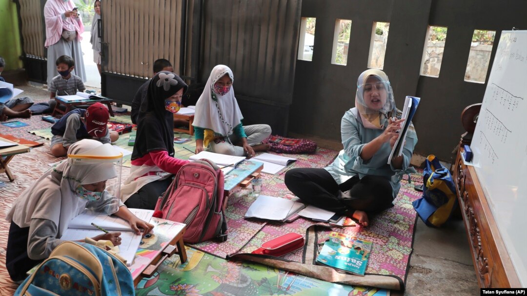 Guru Inggit Andini, kanan, mengajar di kelas darurat bagi siswa yang tidak memiliki akses internet untuk belajar online, di Tangerang, 10 Agustus 2020, sebagai ilustrasi. Empat perempuan, yang sebagian termasuk "berdarah biru" memilih menjadi guru. (Foto: AP)