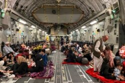 Afghan people sit inside a U S military aircraft to leave Afghanistan, at the military airport in Kabul, August 19, 2021, after the Taliban military takeover of Afghanistan.