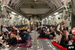 Afghan people sit inside a U S military aircraft to leave Afghanistan, at the military airport in Kabul, August 19, 2021, after the Taliban military takeover of Afghanistan.