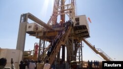 FILE - Engineers and visitors view an exploratory well near Dharoor town, from the port of Bosasso on the Gulf of Aden in Puntland, Somalia, Jan. 17, 2012.