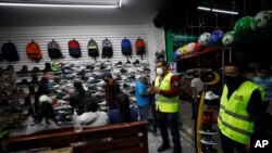 Funcionarios municipales de salud pública en Ecatepec, estado de México, informan a empleados y clientes de una zapatería que el negocio debe cerrar a las 5pm de acuerdo a nuevas restricciones por COVID.