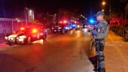 A Federal police officer stands on guard at the area where at least five people including a ministerial police officer were killed in Puerto Juarez, Cancun, Quintana Roo State, Mexico, on July 27, 2018. - A journalist was murdered Tuesday in southeast…