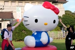 Tourists from Britain pose with Hello Kitty decoration at the Tokyo National Museum where the exhibition "As I change, so does she" is held, marking the 50th anniversary of Hello Kitty in Tokyo, Oct. 30, 2024.