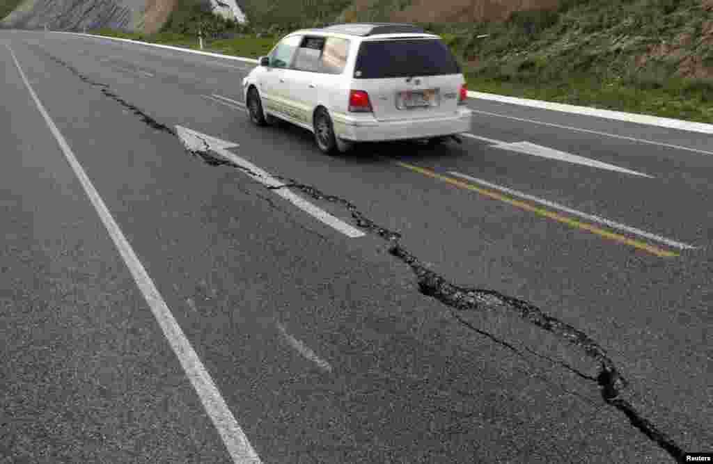 A car drives past a crack in a road after an earthquake on the outskirts of the town of Seddon in the Marlborough region on New Zealand&#39;s South Island. A magnitude 6.5 earthquake struck south of New Zealand&#39;s capital, sending panicked Wellington workers and residents into the streets, but caused little major damage.