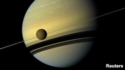 Titan, Saturn's largest moon appears before the planet as it undergoes seasonal changes in this natural color view from NASA's Cassini spacecraft in this handout released by NASA August 29, 2012. The moon measures 3,200 miles, or 5,150 kilometers, across