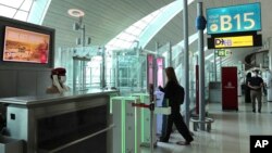 সংযুক্ত আরব আমিরাতে দুবাই বিমানবন্দরে মিডিয়া সফর চলাকালীন এক নারী বিমানে চড়ার জন্য মুখ এবং আইরিস -সনাক্ত গেটে প্রবেশ করছেন। ৭ মার্চ ২০২১।