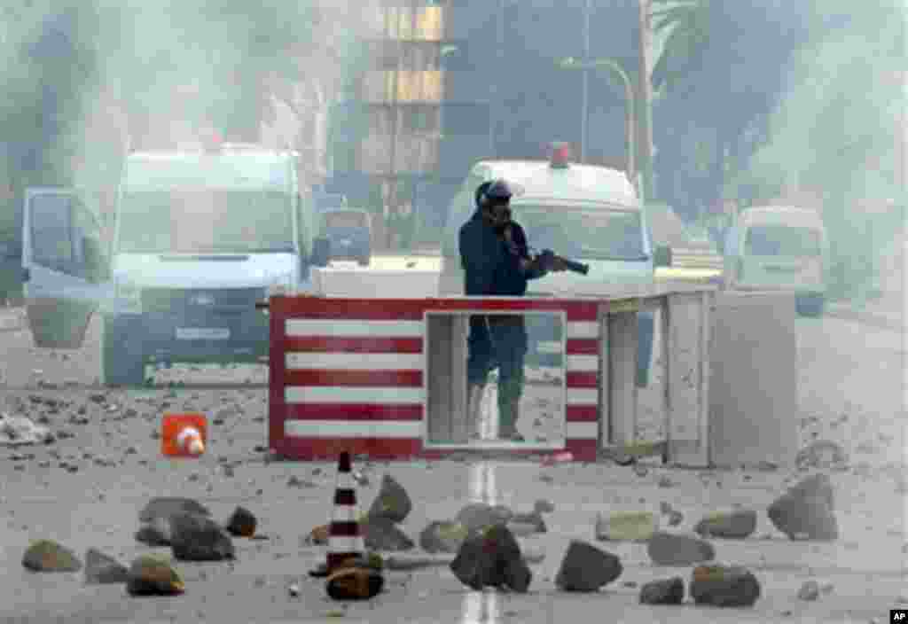 A Tunisian riot police officer holds his weapon during riots in Tunis, Friday, Jan. 14, 2011. Tunisia's president declared a state of emergency and announced that he would fire his government as violent protests escalated Friday, with gunfire echoing in t