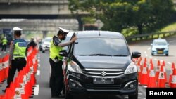 Seorang polisi memeriksa mobil di sebuah pos pemeriksaan ketika para pemudik kembali ke ibu kota di tengah pandemi COVID-19, di Cikarang, Bekasi, 17 Mei 2021. (REUTERS/Ajeng Dinar Ulfiana)
