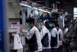FILE PHOTO: Employees wearing face masks work on a car seat assembly line at Yanfeng Adient factory in Shanghai, China, as the country is hit by an outbreak of a new coronavirus, February 24, 2020.