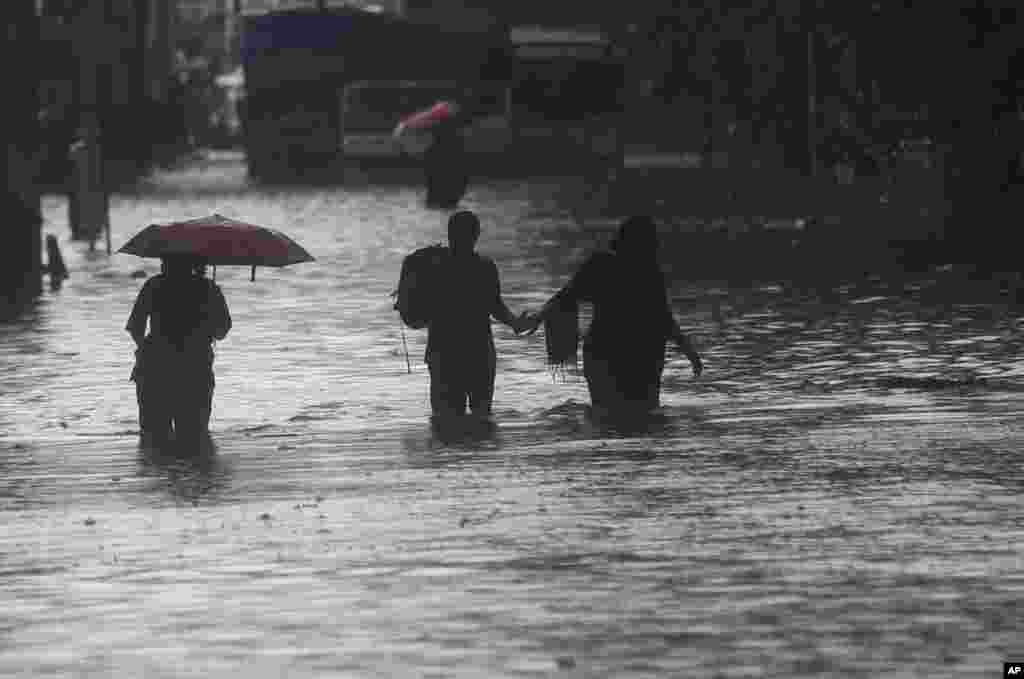 عبور مردم از خیابان‌های آب‌گرفته، حین بارندگی‌های شدید در بمبئی، هند