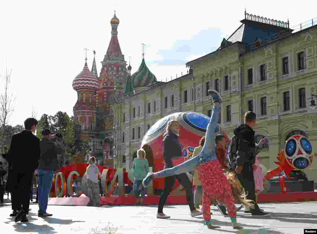 Warga berjalan melewati dekorasi-dekorasi menjelang Piala Dunia FIFA 2018 dengan latar Katedral St. Basil, di pusat kota Moskow, Rusia, 7 Juni 2018. (Foto: Reuters)